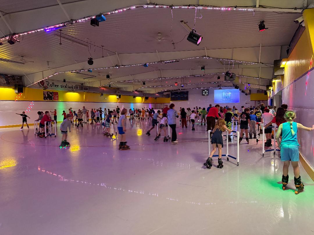 Crowded indoor roller skating rink with colorful lights